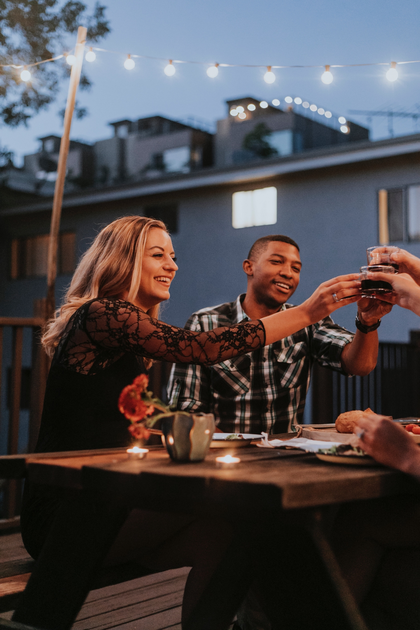 man and woman toasting drink with group of friends at outdoor wood table